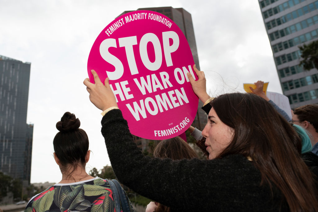 An activist holding a placard that says "Stop The War On Women"