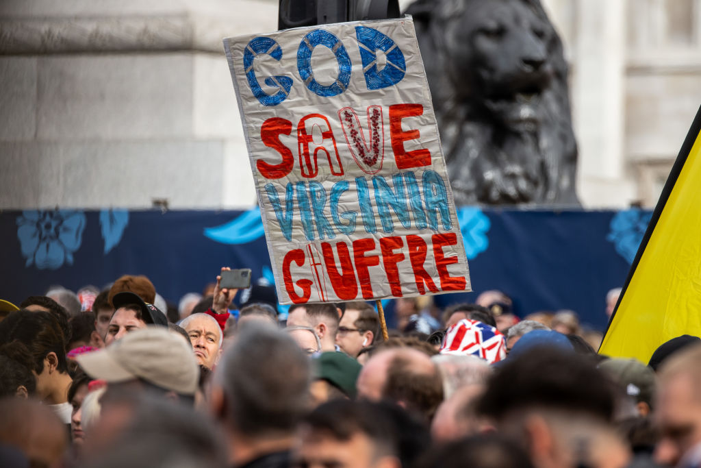 A sign referencing Virginia Giuffre is held aloft in Trafalgar Square