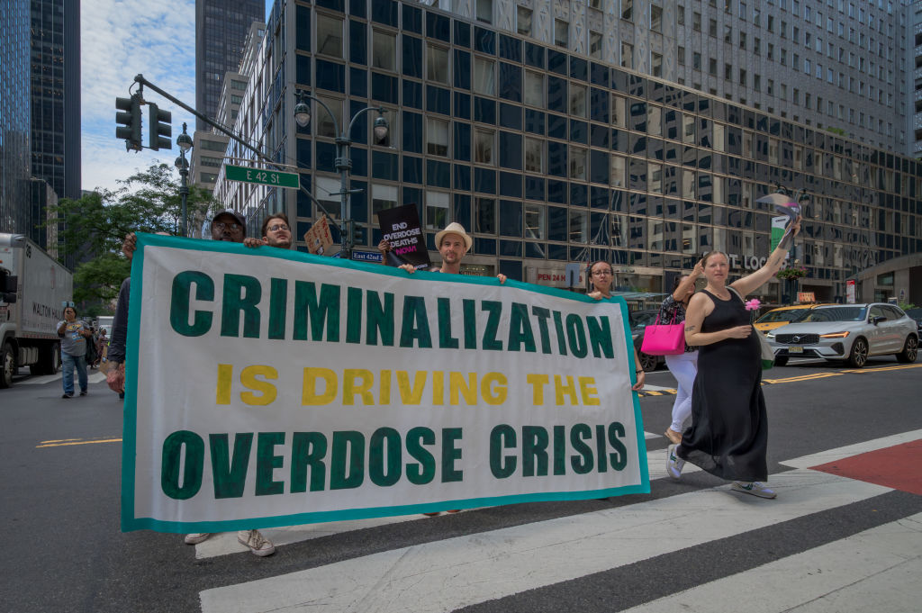 Participants seen holding a banner at a protest in a New York City street: "Criminalization is driving the overdose crisis."