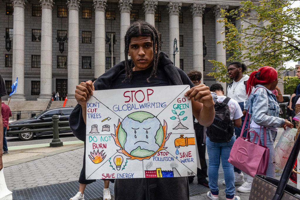 A young man holds a "Stop Global Warming" sign 