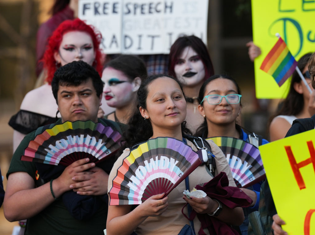 Attendees hold rainbow fans that say "Howdy"