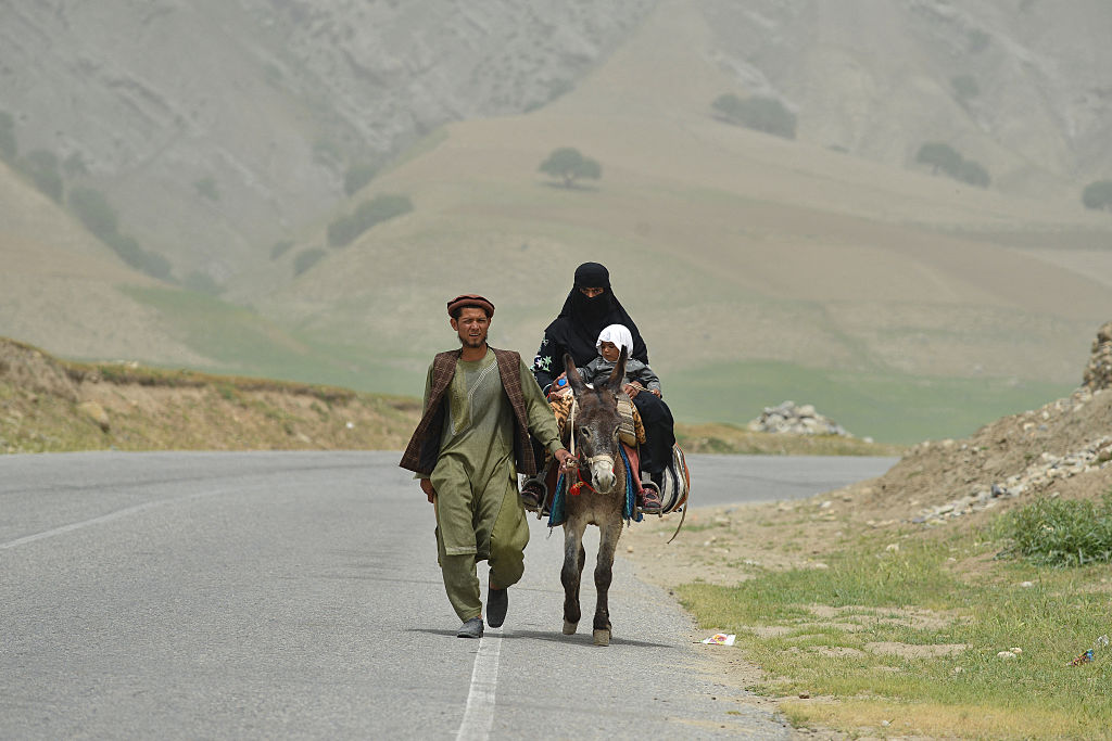 An Afghan man, woman and child riding a donkey